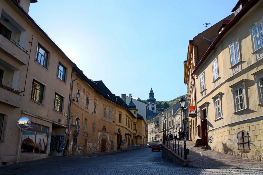 Historická ulica európskeho mesta so starými budovami a slnečným svetlom.